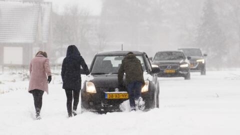 People push a car stuck after heavy snowfall in Haarlem, near Amsterdam, the Netherlands, on February 7, 2021