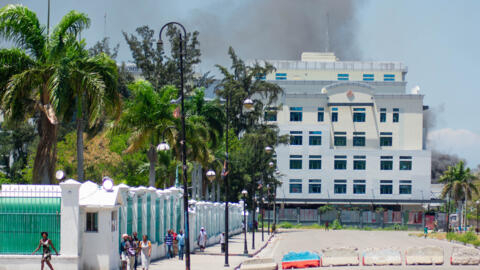 Alors que de la fumée s'échappe du bâtiment du ministère des Finances, des personnes quittent la zone après avoir entendu des coups de feu tirés par des gangs armés près du Palais national à Port-au-Prince, Haïti, le 2 avril 2024.