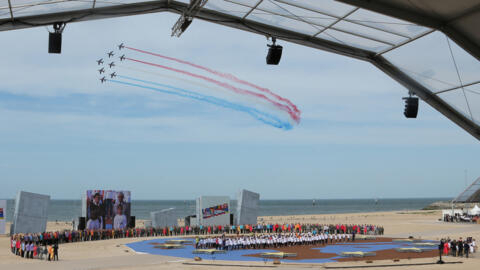 Alpha jets, part of the Patrouille Acrobatique de France, leave trails of smoke in the colors of the French flag while dancers and children perform on June 6, 2014 in Ouistreham, Normandy, during the 