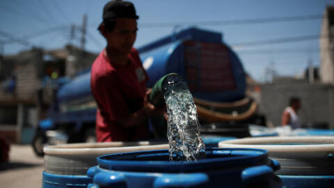 Un homme remplit des réservoirs avec de l'eau provenant d'un camion-citerne distribuant gratuitement de l'eau dans le quartier d'Iztapalapa, à Mexico, le 14 mars 2024.