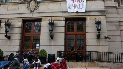 Student protesters sit and watch outside Hamilton Hall, where students at Columbia University continue protesting in support of Palestinians and barricaded themselves inside the building despite order