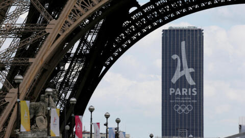 صورة لشعار أولمبياد باريس 2024 وراء برج إيفل.
