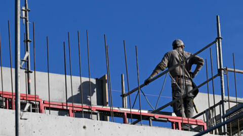 In this file photo, a worker without a helmet stands at a construction site for a new apartment block in France. 