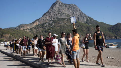 Russian tourists walk to take a boat trip from the beach at Adrasan resort, west of Antalya, Turkey on Saturday, October 1, 2022.