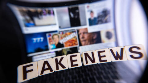 This illustration photograph shows letters reading "fake news" seen through a magnifying glass, against a laptop screen displaying other illustration images of various alleged fake news.