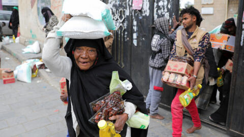 أشخاص يحملون مواد غذائية وزعتها المنظمة الخيرية المحلية منى ريليف في صنعاء، اليمن. (14 مارس 2024)