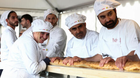 French bakers stand near a large rotating oven in an attempt to beat the world record for the longest baguette during the Suresnes Baguette Show in Suresnes near Paris, 5 May, 2024.