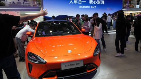 Des visiteurs du salon de l'automobile de Pékin devant une Xiaomi SU7, le 28 avril 2024.