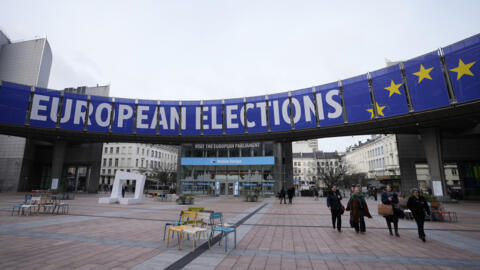 People walk under a banner advertising the European elections outside the European Parliament in Brussels.