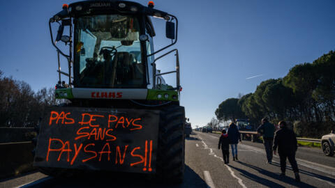 A tractor with a placard reading "no country without farmers" blocking the A64 highway south of Toulouse as part of a growing farmers' protest against high taxes and declining income, 20 January 2024. 