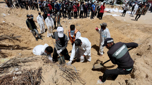 Des personnes travaillent pour déplacer dans un cimetière les corps des Palestiniens tués pendant l'offensive militaire israélienne et enterrés à l'hôpital Nasser, à Khan Younès, dans le sud de la bande de Gaza, le 21 avril 2024.