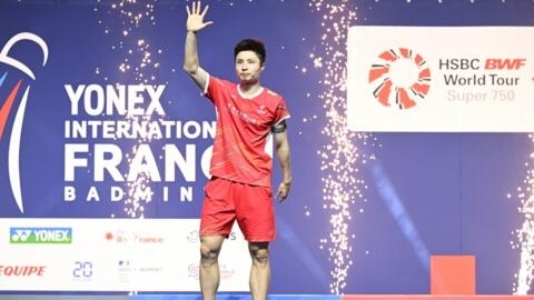 Shi Yu Qi celebrates on the podium after winning the men's singles title at the French Open badminton tournament.