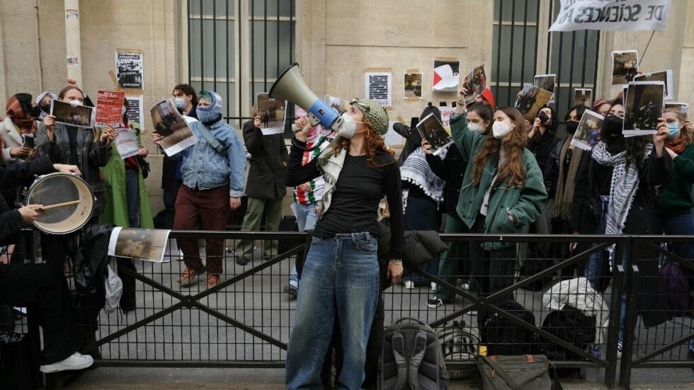 A demonstrator speaks in a megaphone wearing Palestinan keffiyeh as students occupy a building of Sciences Po in Paris.