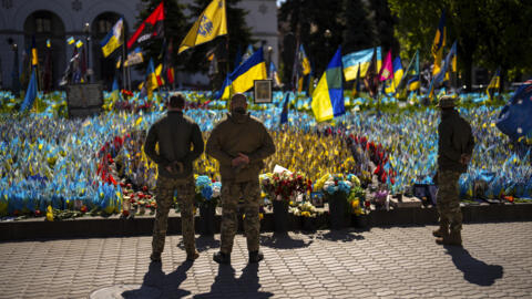 Военнослужащие стоят рядом с украинскими флагами и фотографиями, размещенными в память о мирных жителях и солдатах, погибших во время войны. Киев, Майдан Незалежностi. 20.04.2024