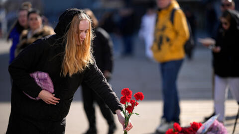 Девушка возлагает цветы у стихийного мемориала жертвам теракта в подмосковном концертном зале в «Крокус Сити Холле». 27 марта 2024 года.
