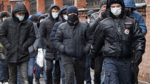 Полицейский сопровождает группу мигрантов, приехавших продлить разрешение на работу, в миграционный центр в Санкт-Петербурге. 2 апреля 2020 года