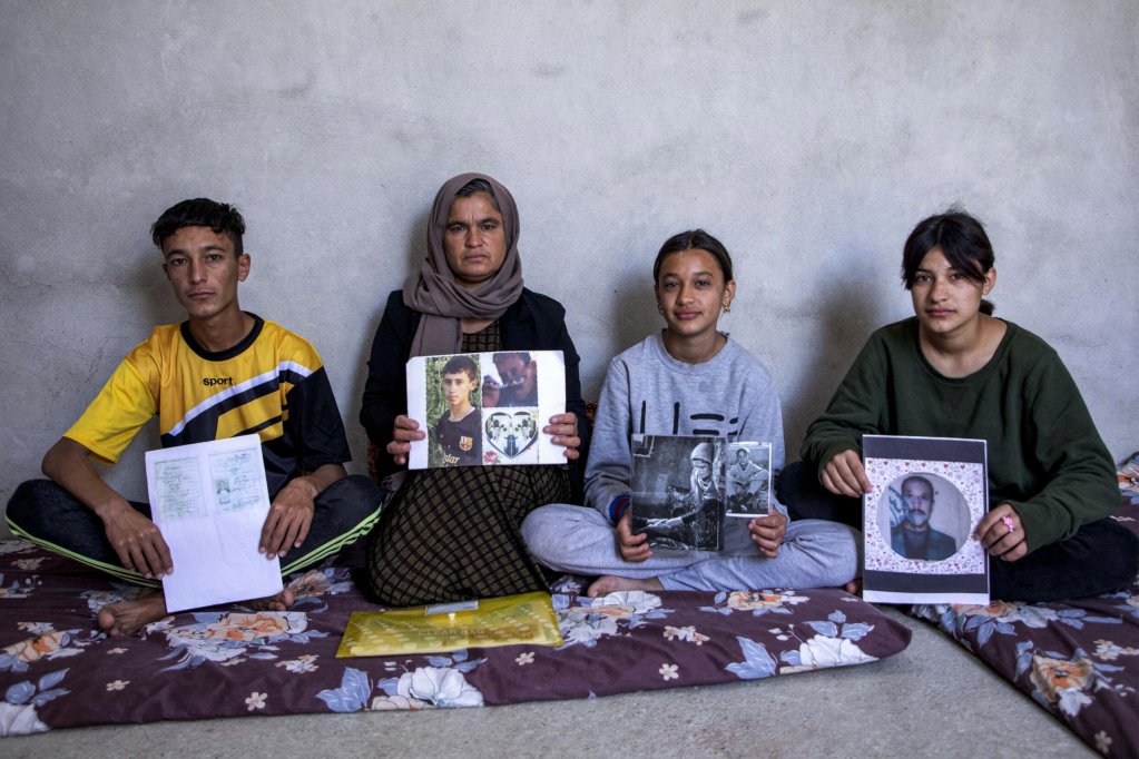 Yazidi woman Bahar Elias with her son and daughters at the Sharya camp in northern Iraq on April 22, 2023, holding photos of family members kidnapped by IS | Photo: Safin Hamid / AFP  