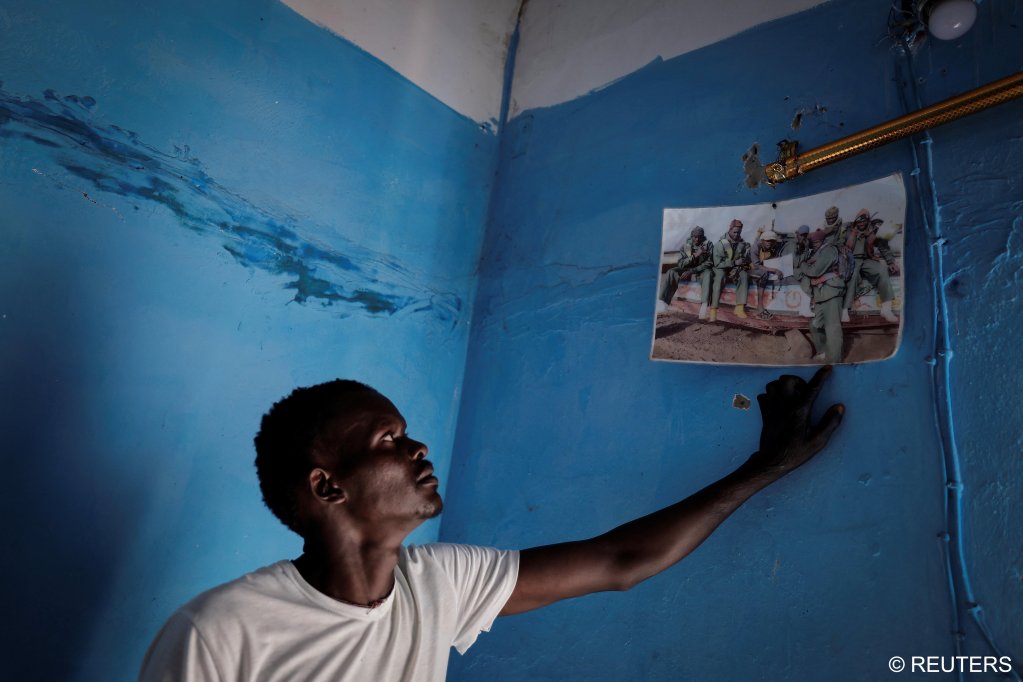 Fisherman Birane Mbaye, points at a group picture on his wall which shows his fishermen friends, three of whom have succeeded in their journey to reach Spain, one who died at sea and others who are still in Fass Boye, Senegal, March 19, 2024. | Photo: REUTERS/Zohra Bensemra 