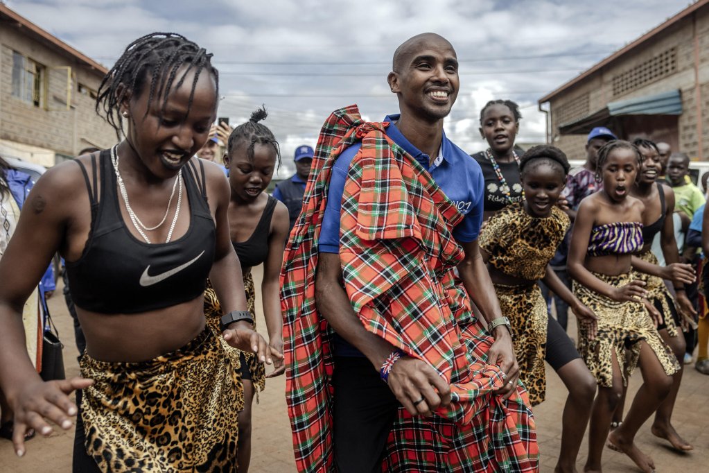 Le coureur à la retraite somalo-britannique Mo Farah (C) danse avec de jeunes danseurs kényans lors de son arrivée pour participer au tournoi annuel Mo Farah Football Cup pour les migrants urbains à la Mathare Youth Sports Association à Nairobi, le 21 avril 2024. Crédit : AFP