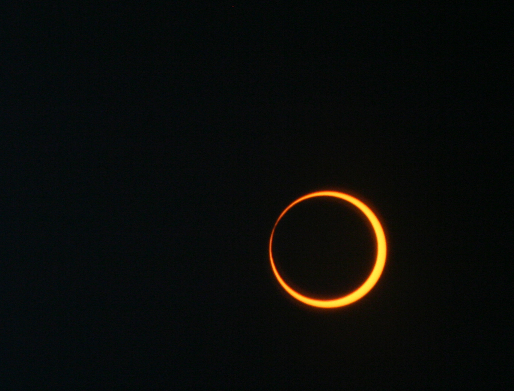 Most of the Sun is blocked by the dark Moon in this photo. The Moon is outlined in bright sunlight, similar to a ring of fire.