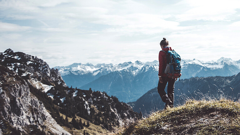 Frau mit Rucksack beim Wandern in den Bergen.