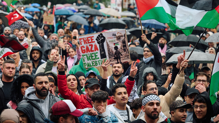 Teilnehmer einer pro-palästinensischen Demonstration in Hagen schwenken Fahnen und zeigen Plakate.