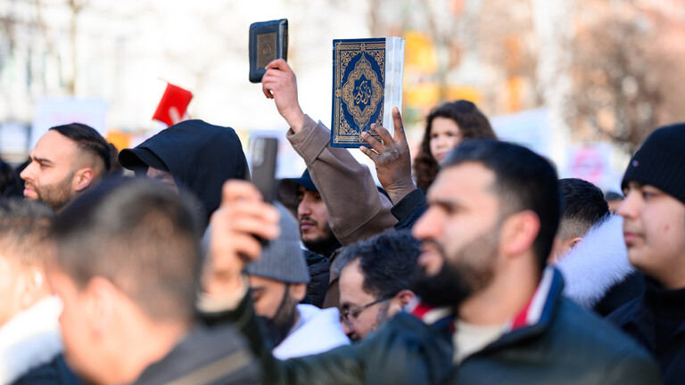Teilnehmer einer Demo in Hamburg 2023 halten den Koran in die Höhe.