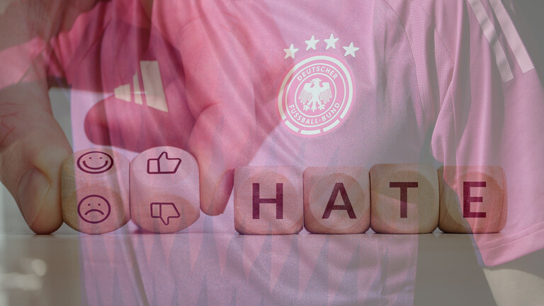Nahaufnahme neues pinkes DFB Trikot Auswärtstrikot / Hand hält zwei Würfel mit thumb up und down, „HATE“ steht auf vier Würfeln
