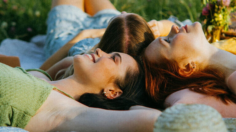 Drei Freundinnen liegen im Gras.