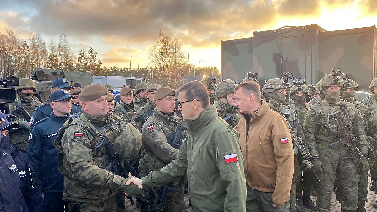 Poland's Prime Minister Mateusz Morawiecki (C) and Defence Minister Mariusz Blaszczak (R) meet border guards and troops at Kuznica, Poland-Belarus border, Nov. 9, 2021.