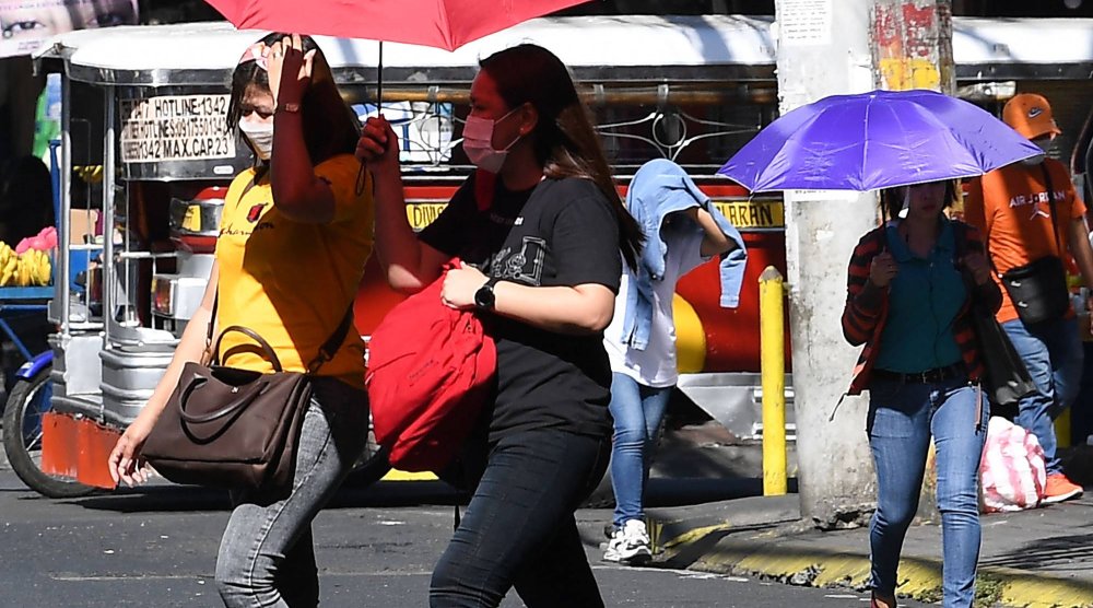 People walk with umbrellas during a heatwave in Manila on April 29, 2024. (Photo by Ted ALJIBE / AFP)