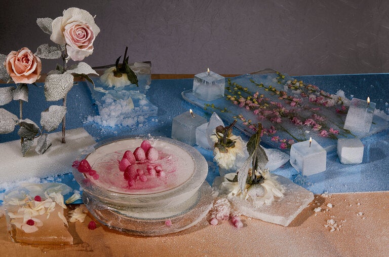 From left: frozen peony petals, berry-shaped ice atop an ice-enclosed plate, ice cube candles and delphinium spray flowers inside sheet ice.