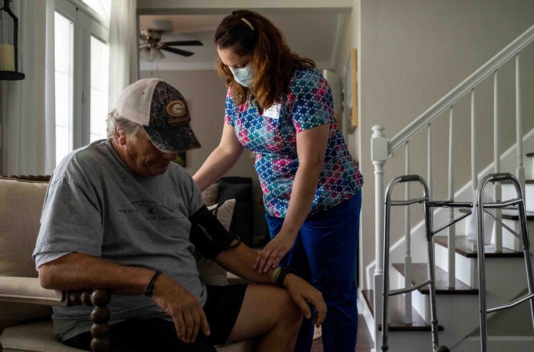 April Abel, a former home health nurse at Roper St. Francis Healthcare, in the home of a patient, Ron Keur, in Summerville, S.C., in 2022.