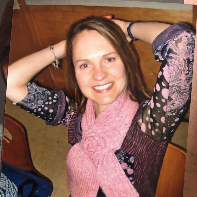 A photograph of a photograph of a woman leaning back on her hands, wearing a printed shirt and a pink scarf.