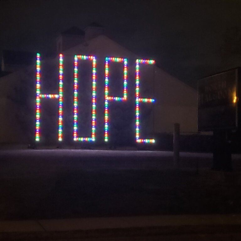 The word “hope,” created in lights on a lawn in front of a house.