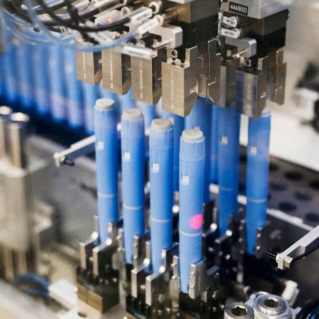 A row of blue plastic pen devices on a factory production line.