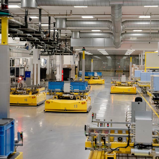 Yellow robotic machinery moving products around a factory. 