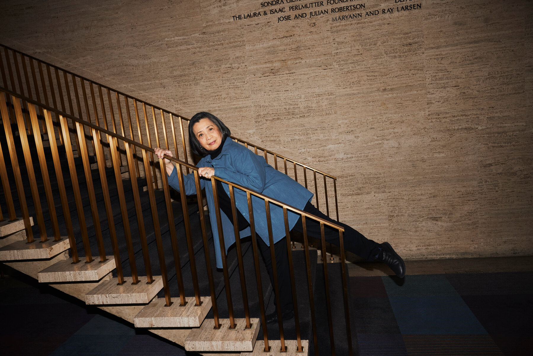 Mia Katigbak leans forward with her left leg in the air holding a railing with both hands.