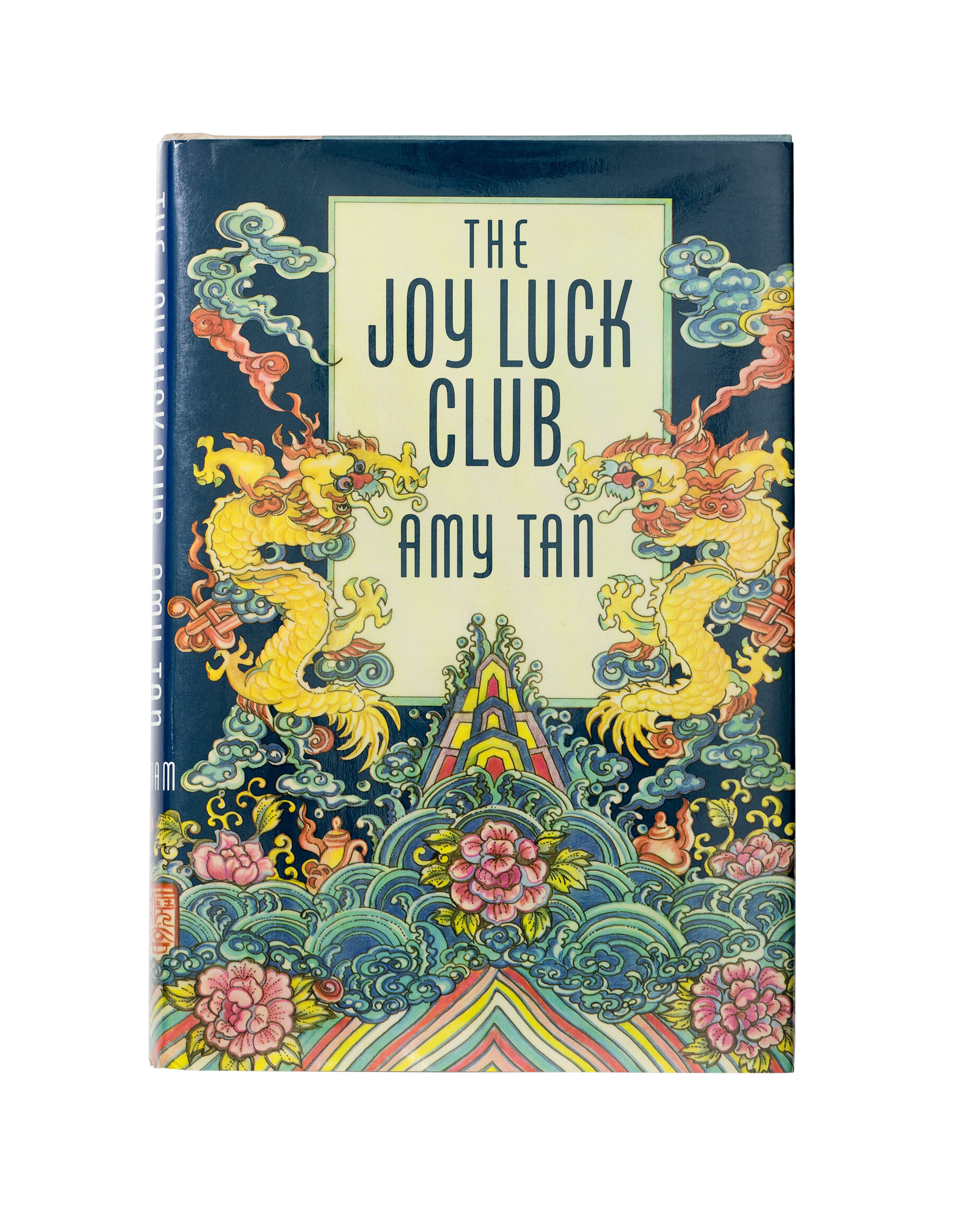 A cover of the book "The Joy Luck Club" with illustrations of dragons and a mirrored cloud-like pattern.