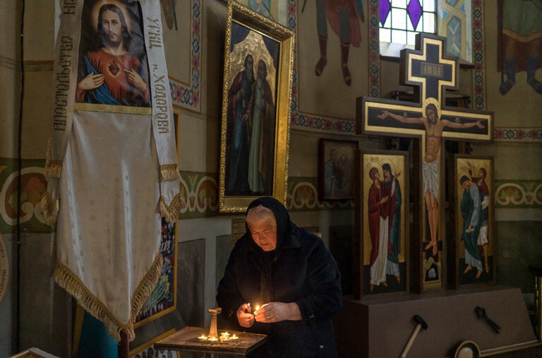 Aghaphia Vyshyvana lighting a candle in memory of her two sons, Vasyl and Kyrylo Vyshyvany, who died fighting in the war in 2022, in Khodoriv, Ukraine, last month.