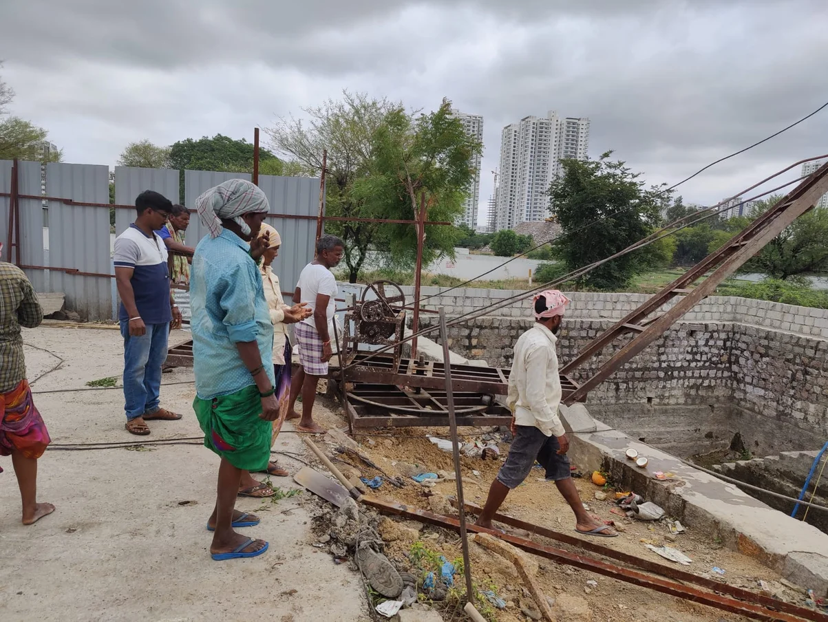 A group of workers repair a water well.