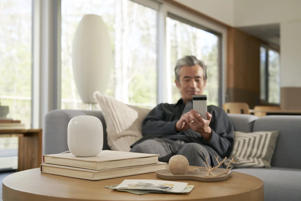 Man sitting on couch setting up a Nest Wifi Pro with his Pixel device