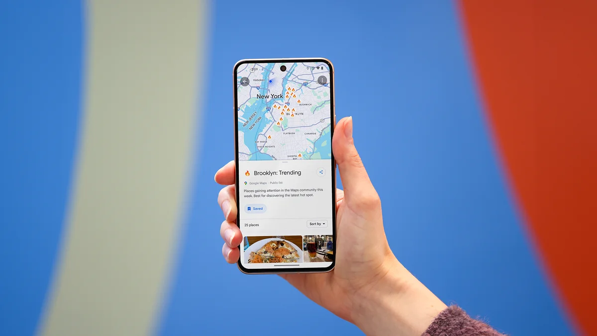 A photo of a hand holding up a phone with Google Maps open. The screen shows the top of a trending restaurant list in Brooklyn, NY.
