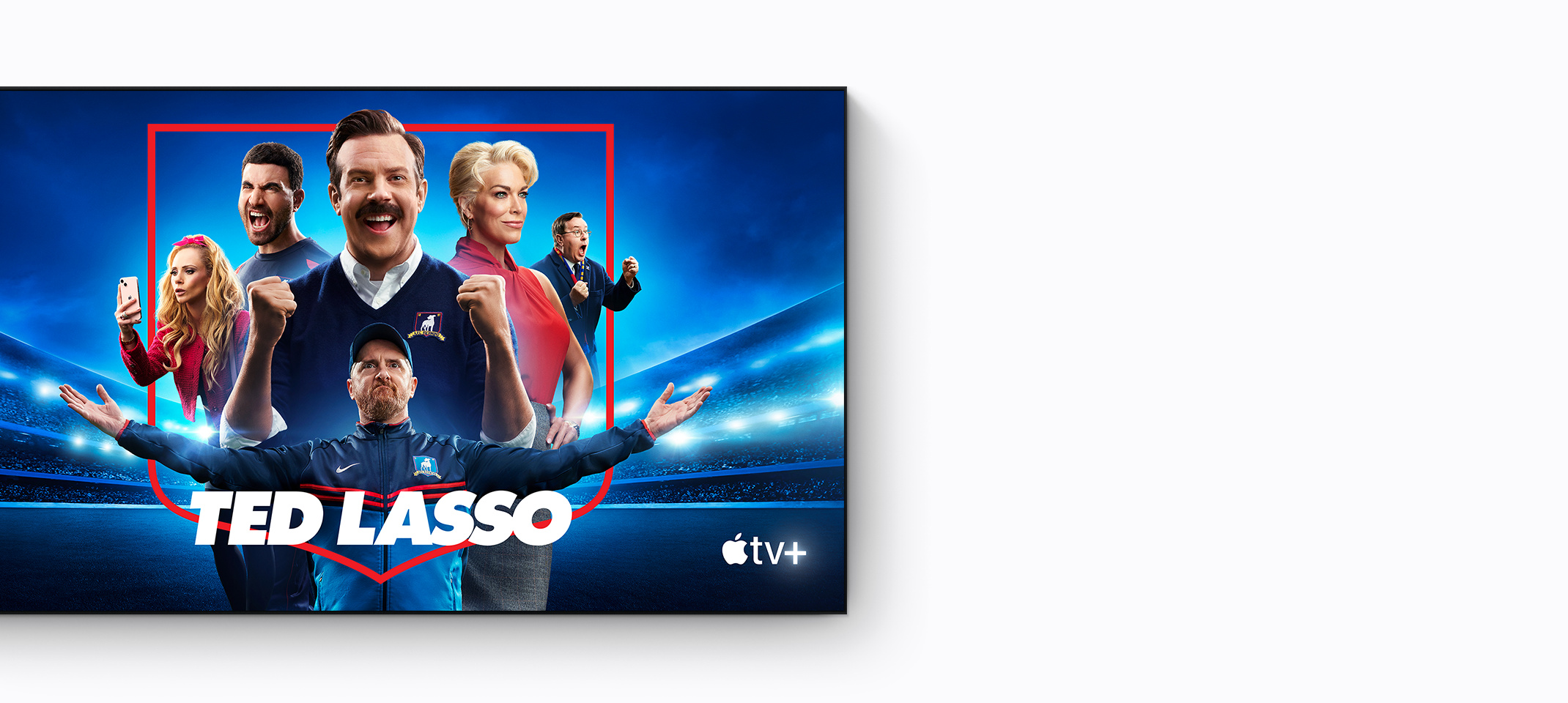 Ted Lasso on Apple TV+ starring Jason Sudeikis, smiling, pumping fists, Brendan Hunt, arms stretched wide in triumph, Brett Goldstein shouting powerfully in celebration, Juno Temple snapping a photo with her iPhone, Hannah Waddingham staring contemplatively into the distance, all centred in the red outline of a club crest, football stadium shrouded in blue and black