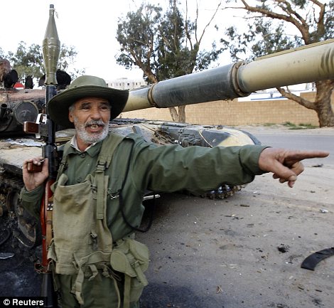 Defiant: An elderly rebel fighter stands in front of a destroyed tank in Benghazi
