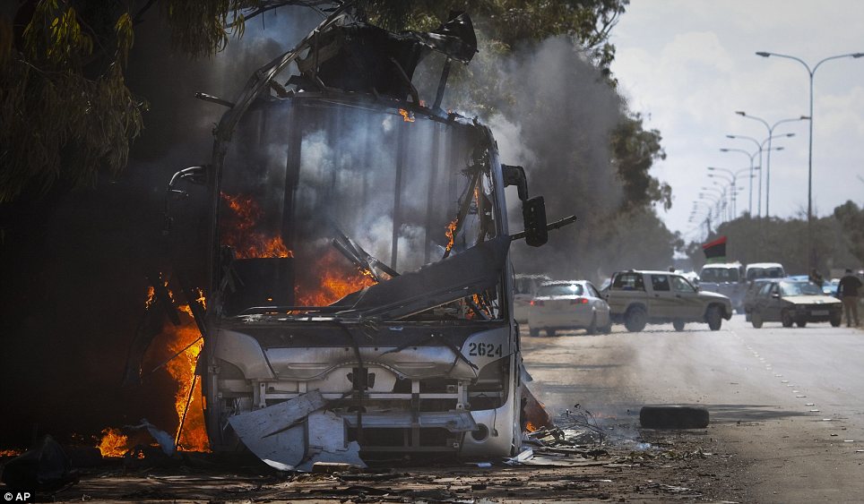 In flames: A bus burns on a road leading to the outskirts of Benghazi. The U.S. military said 112 Tomahawk cruise missiles were fired from American and British ships and submarines