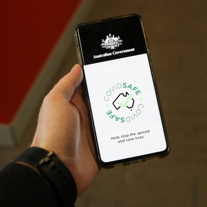 A mobile phone held in a person's left hand shows the homepage of a government health app.