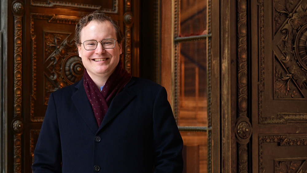 William Deringer smiles while standing next to an ornate wooden door