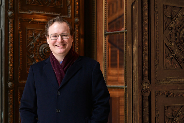 William Deringer smiles while standing next to an ornate wooden door