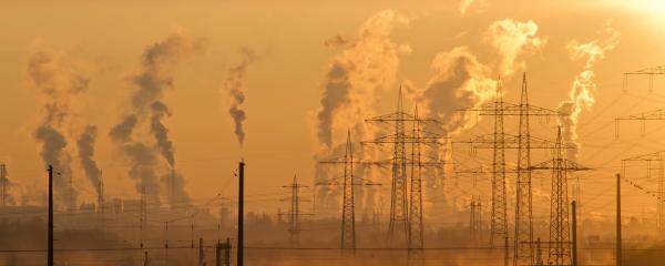 Smoke rises from a power plant at sunset.